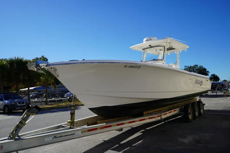 Slide: The Image of 2021 Edgewater 320CC boat on trailer under clear blue sky. - 2
