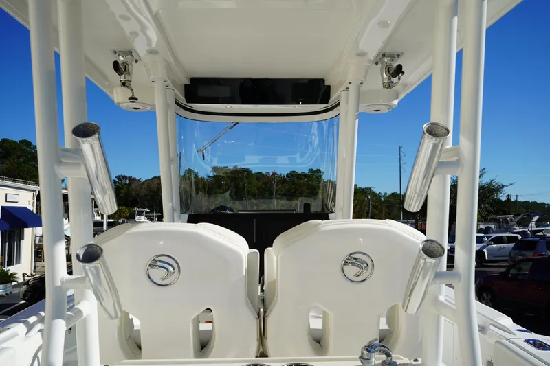 Slide: The Image of 2021 Edgewater 320CC boat interior with rod holders and seating, under clear blue sky. - 23