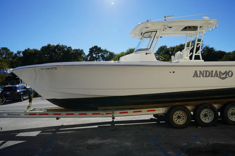Slide: The Image of 2021 Edgewater 320CC boat on trailer, labeled "ANDIAMO," under clear blue sky. - 3