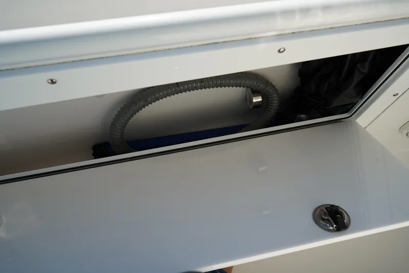 Slide: The Image of Storage compartment in 2021 Edgewater 320CC boat, featuring hose and latch. - 36