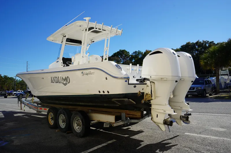 Slide: The Image of 2021 Edgewater 320CC boat on trailer with dual outboard engines, parked outdoors. - 5