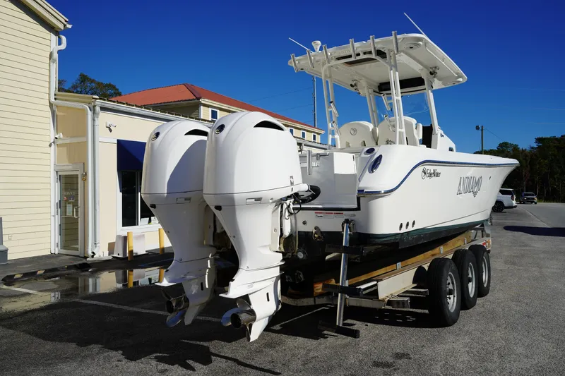 Slide: The Image of 2021 Edgewater 320CC boat on trailer with dual outboard engines, parked near a building. - 7