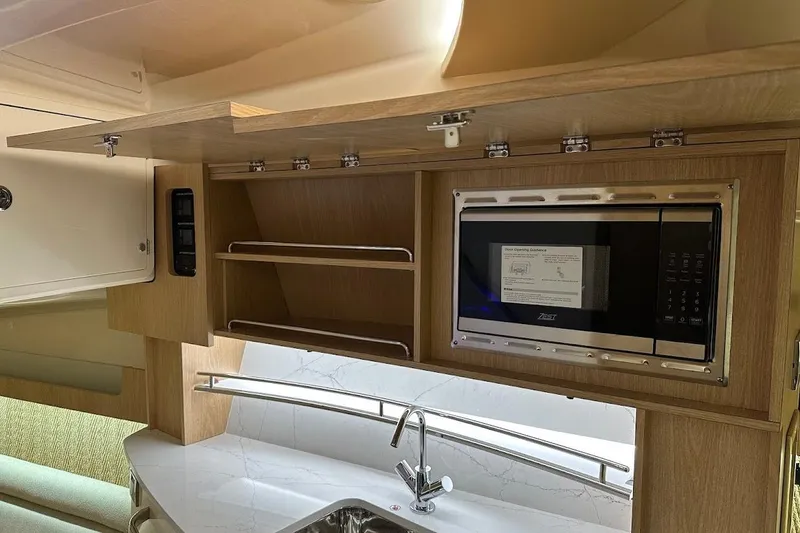 Slide: The Image of 2026 Grady-White Express 340 interior kitchen with microwave and modern cabinetry. - 27