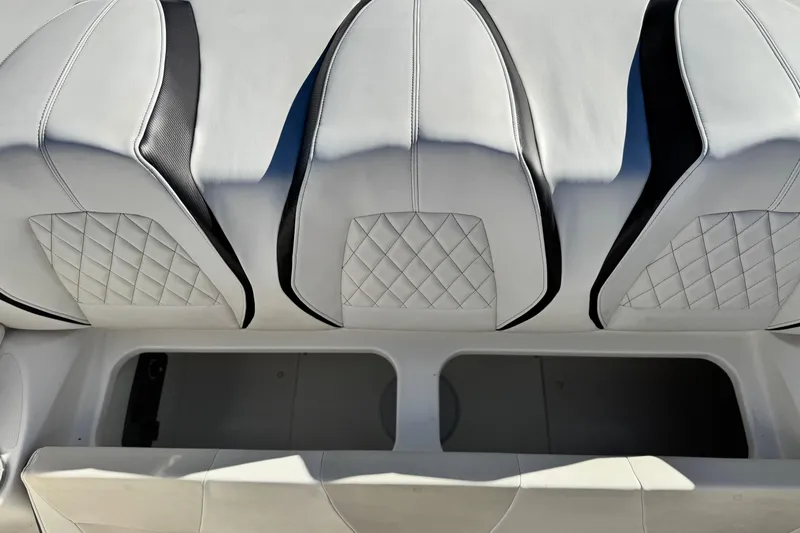 Slide: The Image of 2019 Baja 27 Outlaw boat interior with white quilted seats and storage compartment. - 14