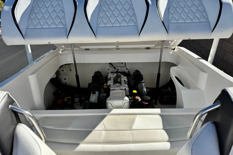 Slide: The Image of 2019 Baja 27 Outlaw boat engine compartment with V8 engine, open seating, and white upholstery. - 16