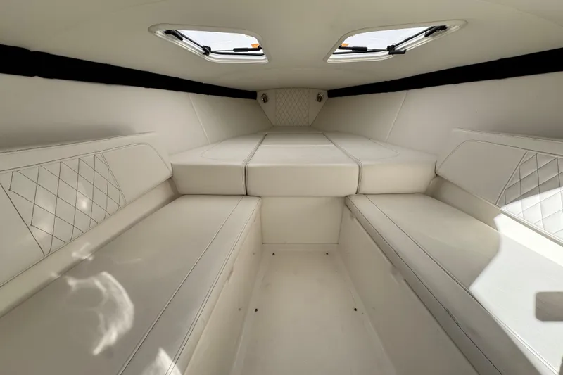 Slide: The Image of 2019 Baja 27 Outlaw cabin interior with white seating and overhead windows. - 27