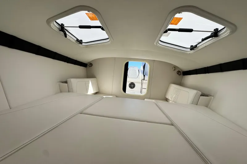 Slide: The Image of Interior cabin of 2019 Baja 27 Outlaw boat with white upholstery and skylights. - 29