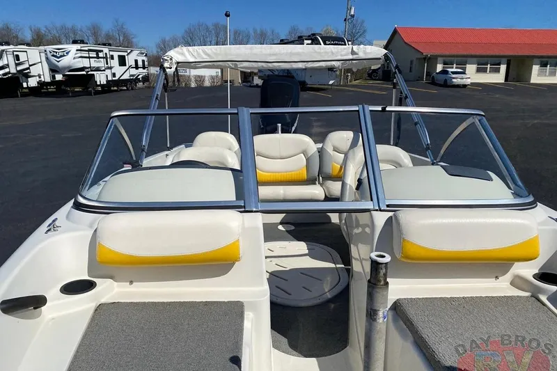 Slide: The Image of 2008 Nitro 189 Sport boat with white and yellow seating, parked near RVs. - 31