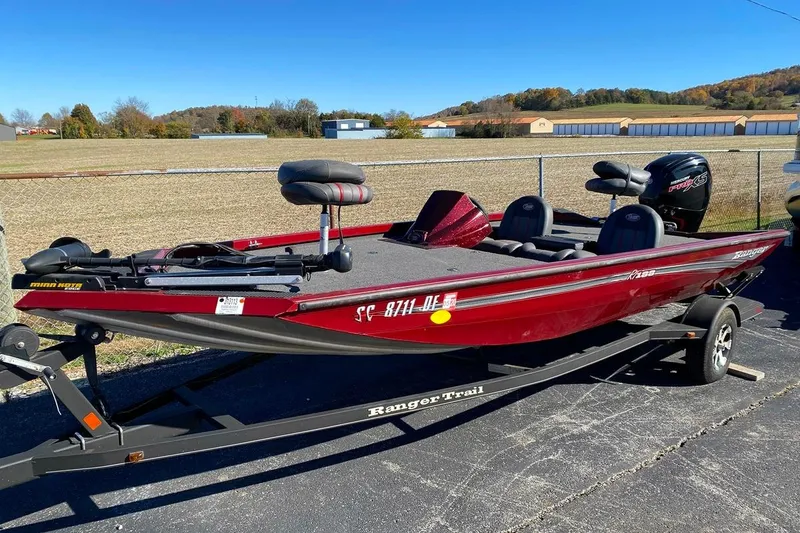 Slide: The Image of 2017 Ranger RT188 boat in red on a trailer, parked outdoors under a clear blue sky. - 14