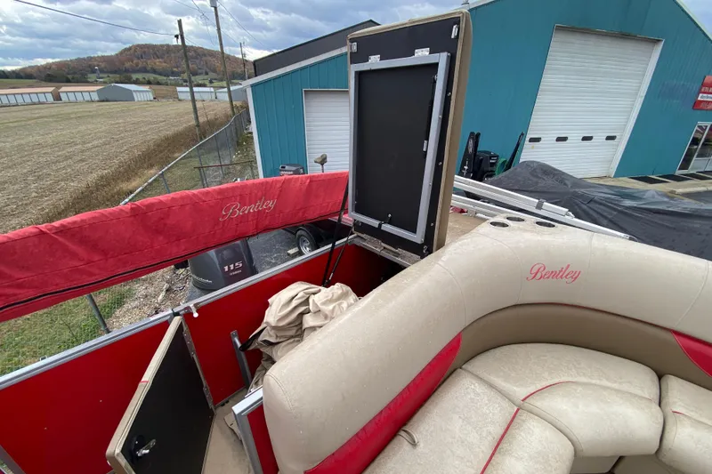 Slide: The Image of 2018 Bentley Pontoons 200 Fish with beige and red interior, docked near a blue building. - 23