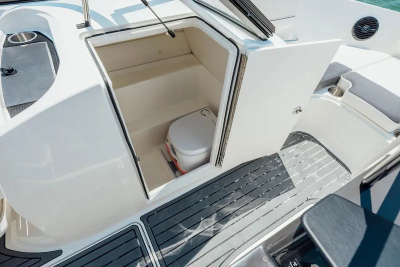 Slide: The Image of 2026 Bayliner VR6 Bowrider OB interior with open storage compartment and portable toilet. - 9