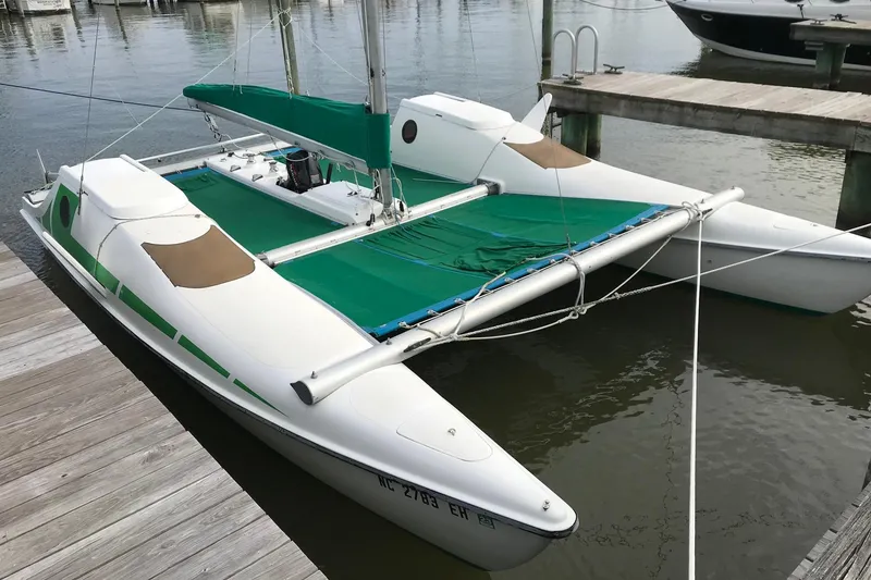 The Image of 1985 Sea Wind 24 trimaran sailboat docked, featuring green accents and white hull. - 1