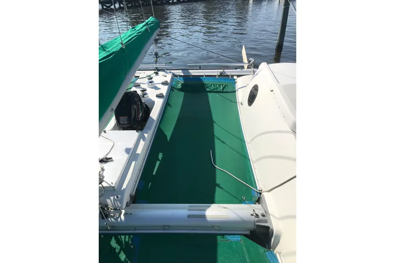 Slide: The Image of 1985 Sea Wind 24 sailboat deck with green cover, docked by calm waters. - 16