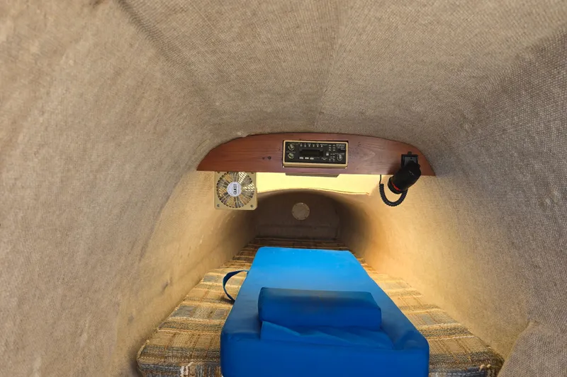 Slide: The Image of Interior of 1985 Sea Wind 24 sailboat cabin with blue cushion and fan. - 21