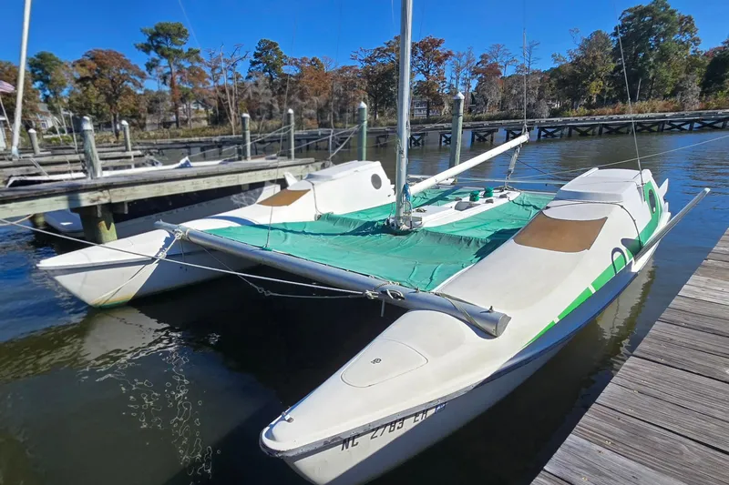 Slide: The Image of 1985 Sea Wind 24 sailboat docked at a marina, featuring a green deck cover. - 31