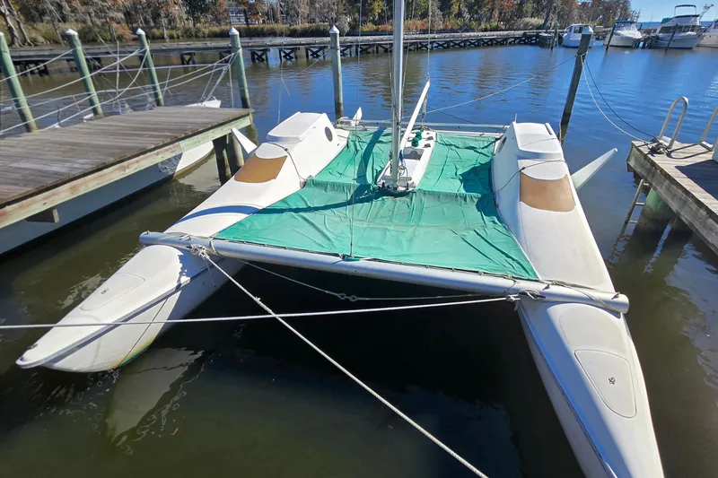 Slide: The Image of 1985 Sea Wind 24 catamaran docked, featuring green cover and sleek design. - 32