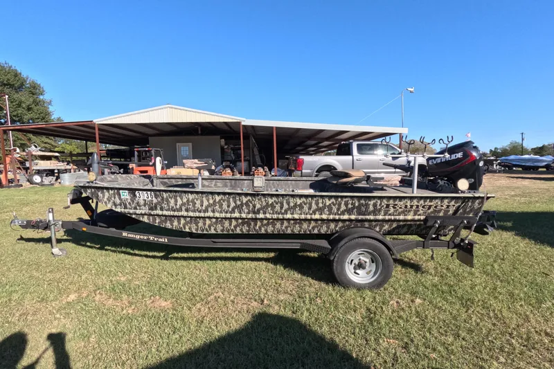 Slide: The Image of 2014 Ranger 1652H MPV boat on trailer, parked outdoors near a metal building. - 6
