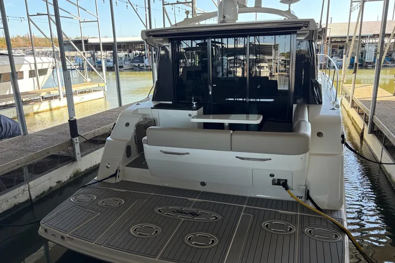 Slide: The Image of 2015 Sea Ray 470 Sundancer yacht docked, showcasing spacious rear deck and seating area. - 54