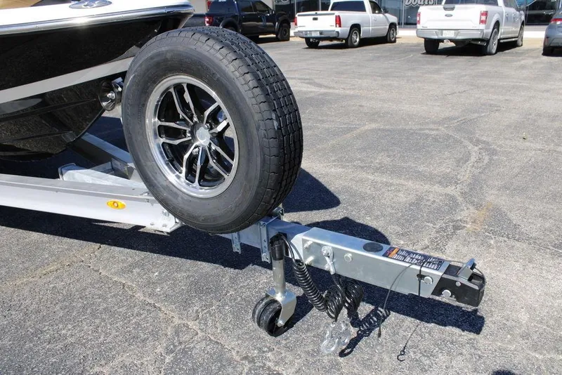 Slide: The Image of 2026 Skeeter SX241 boat trailer with spare tire in a parking lot. - 2