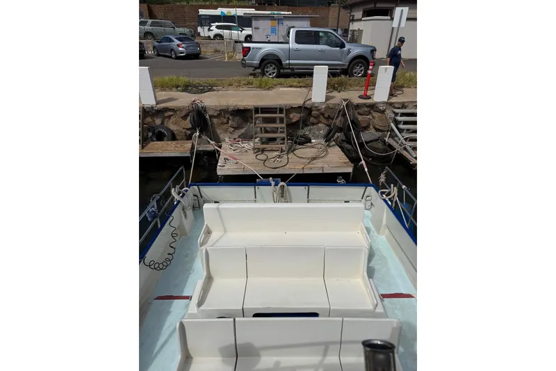Slide: The Image of Douglas Phillips Power Cat 1998 docked, with visible seating and nearby parked vehicles. - 3