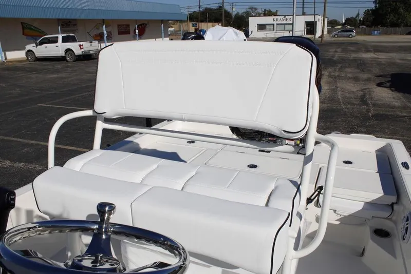 Slide: The Image of 2026 Skeeter SX230 boat interior with white seating and steering wheel in a parking lot. - 17