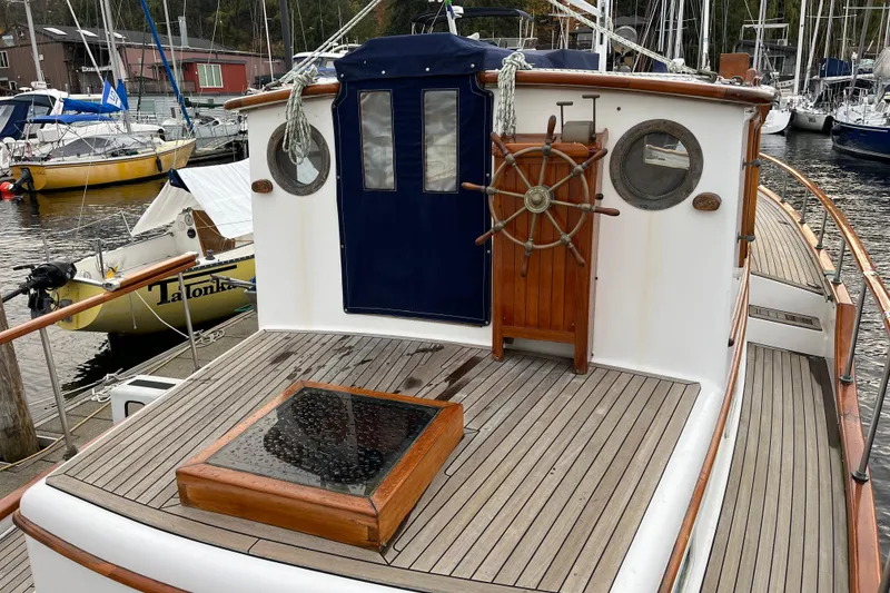 Slide: The Image of 1987 Liberty Gatsby boat deck with wooden steering wheel and portholes, docked at marina. - 32