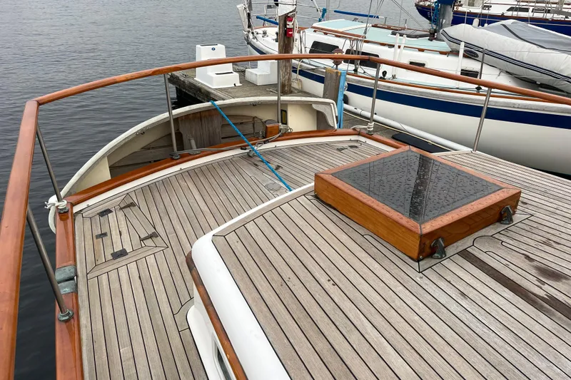 Slide: The Image of 1987 Liberty Gatsby yacht deck with wooden railings and docked sailboats in the background. - 35
