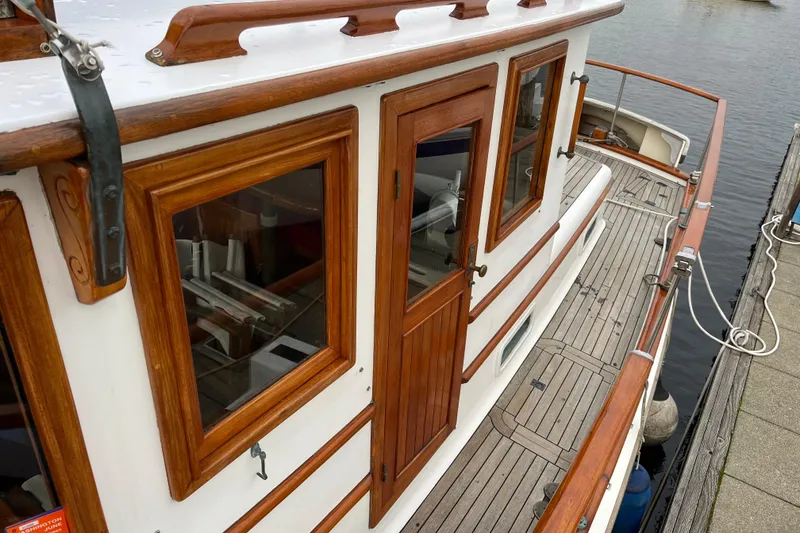 Slide: The Image of 1987 Liberty Gatsby boat with wooden cabin details docked by the water. - 37