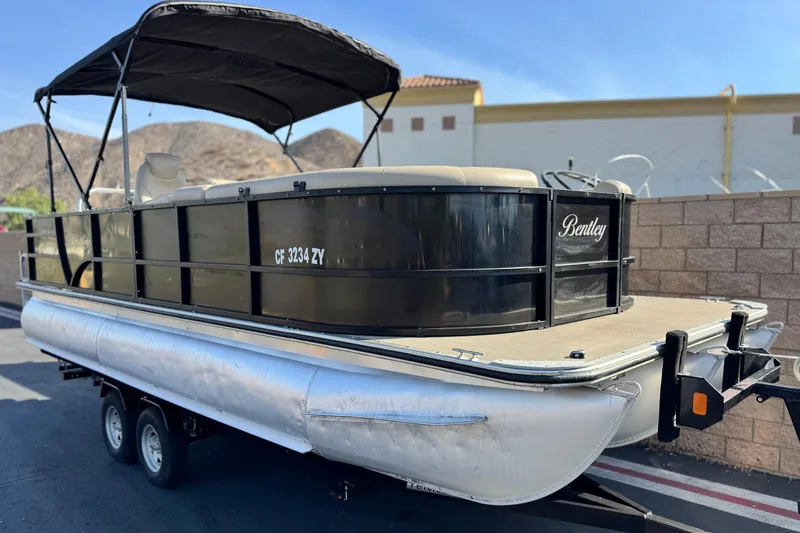 Slide: The Image of 2020 Bentley Pontoons 223 Cruise on trailer, black canopy, parked outdoors. - 1