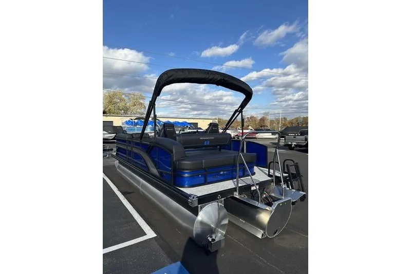Slide: The Image of 2026 Bennington S Swingback 22 SSB pontoon boat with blue and black design, parked outdoors. - 5