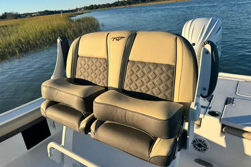 Slide: The Image of 2023 Tidewater 2500 Carolina Bay boat seats with diamond stitching, on a serene water backdrop. - 10