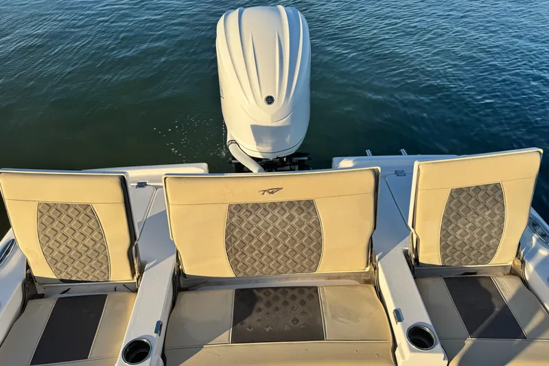 Slide: The Image of 2023 Tidewater 2500 Carolina Bay boat with cushioned seats and outboard motor on water. - 12