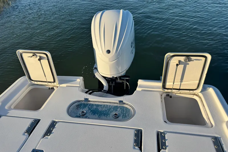 Slide: The Image of 2023 Tidewater 2500 Carolina Bay boat with open storage compartments and outboard motor. - 15