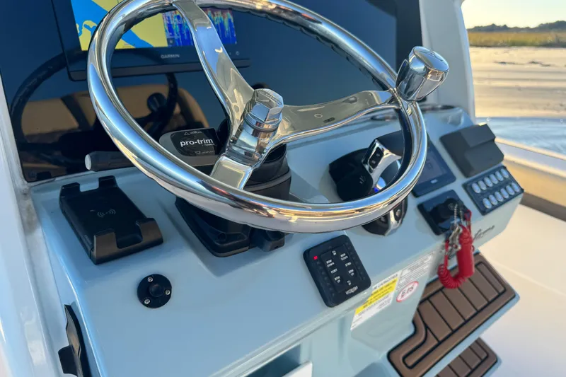 Slide: The Image of 2023 Tidewater 2500 Carolina Bay boat dashboard with steering wheel and controls. - 16