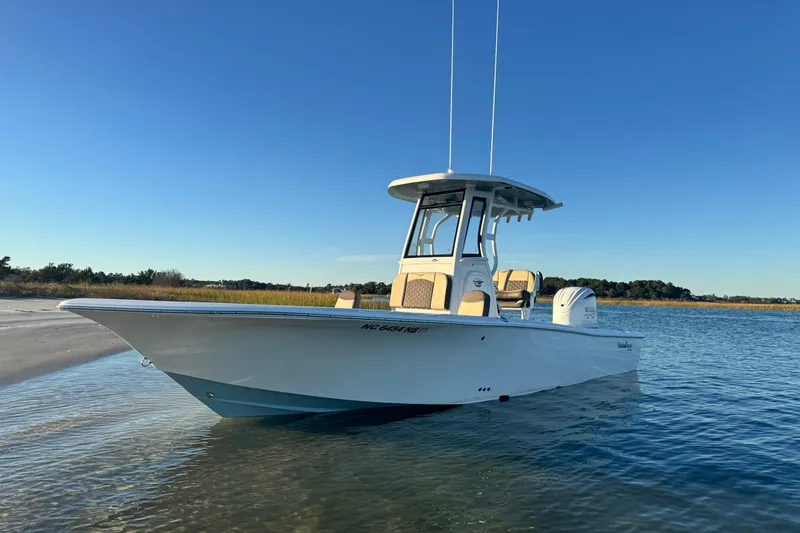 Slide: The Image of 2023 Tidewater 2500 Carolina Bay boat on calm water near sandy shore. - 6