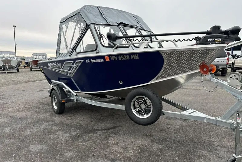 Slide: The Image of 2025 Hewescraft 160 Sportsman boat on trailer, featuring a Minn Kota trolling motor. - 2