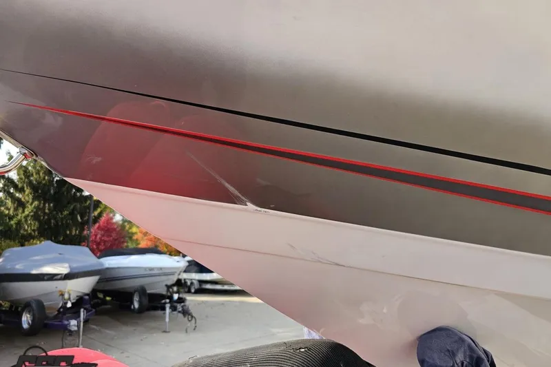 Slide: The Image of 2008 Donzi 38 ZR boat hull with red and black stripes, parked outdoors. - 17