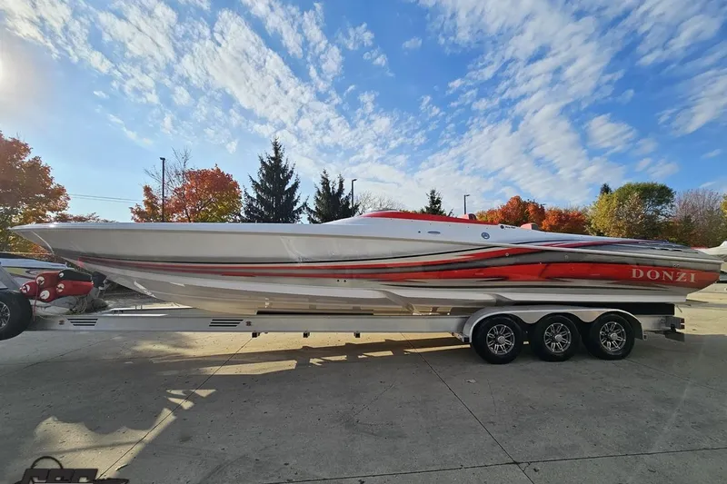 Slide: The Image of 2008 Donzi 38 ZR speedboat on trailer, vibrant red and white design, under clear blue sky. - 19