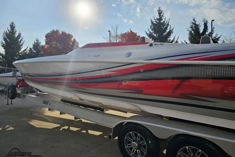 Slide: The Image of 2008 Donzi 38 ZR speedboat with red and black graphics on a trailer, under sunny sky. - 24