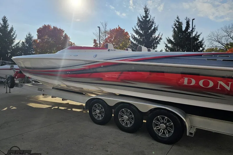 Slide: The Image of 2008 Donzi 38 ZR speedboat on trailer, vibrant red and white design, sunny day backdrop. - 25
