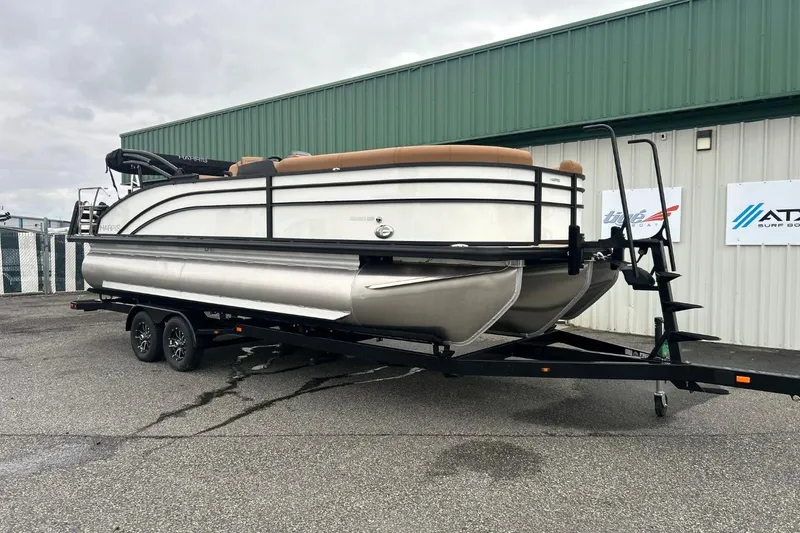 Slide: The Image of 2026 Harris CRUISER 230 SL pontoon boat on trailer, parked outside a green building. - 2