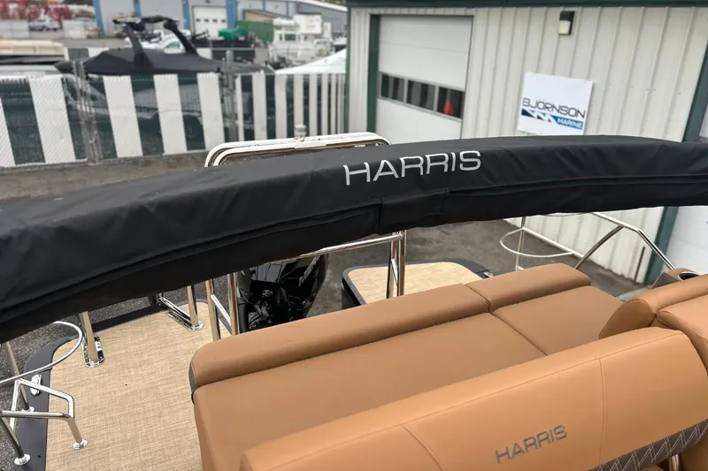 Slide: The Image of 2026 Harris CRUISER 230 SL boat with tan seating and black cover at marina. - 28