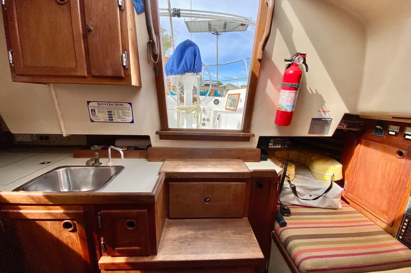 Slide: The Image of 1986 Bayfield 32 sailboat interior with kitchenette, fire extinguisher, and striped seating. - 18