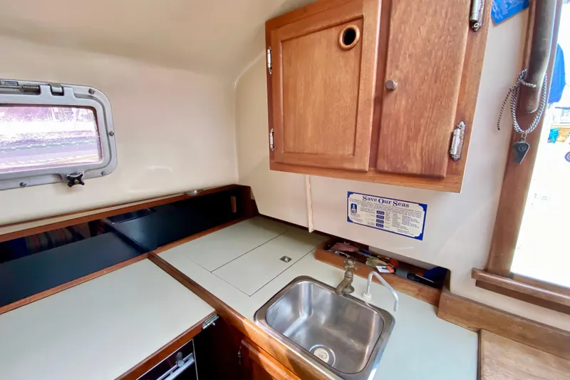 Slide: The Image of Interior of 1986 Bayfield 32 sailboat galley with sink, wooden cabinets, and window. - 19