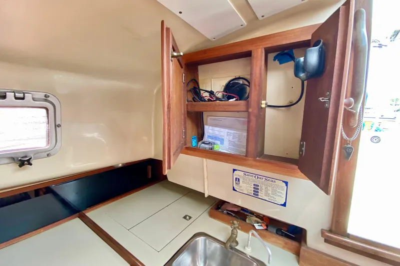 Slide: The Image of 1986 Bayfield 32 sailboat interior with open wooden cabinet and sink area. - 20