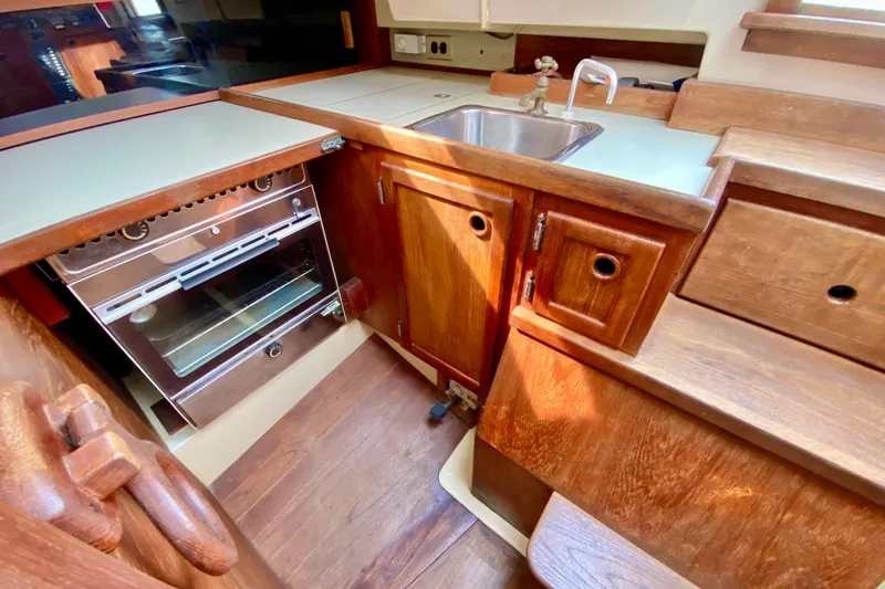 Slide: The Image of 1986 Bayfield 32 yacht kitchen with wooden cabinets, sink, and oven. - 21