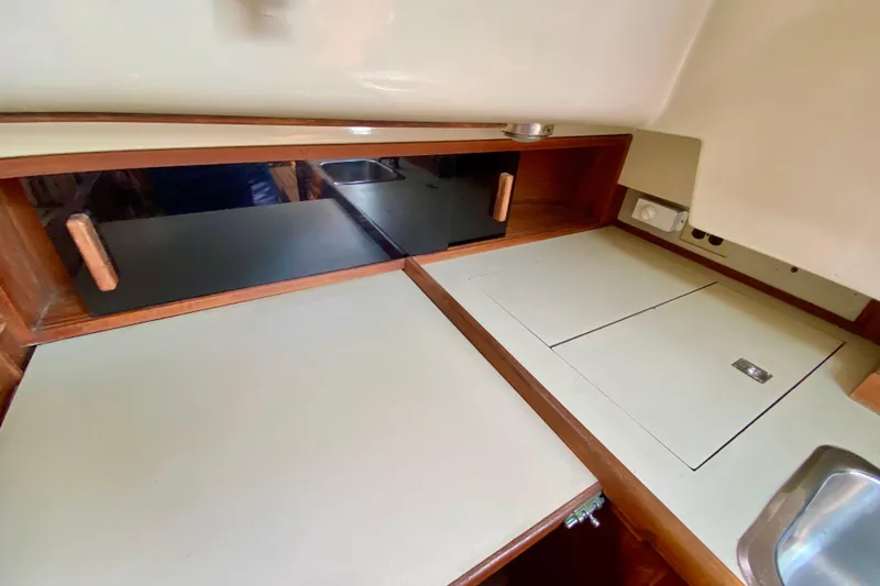 Slide: The Image of 1986 Bayfield 32 yacht interior with wooden cabinetry and compact kitchen area. - 22