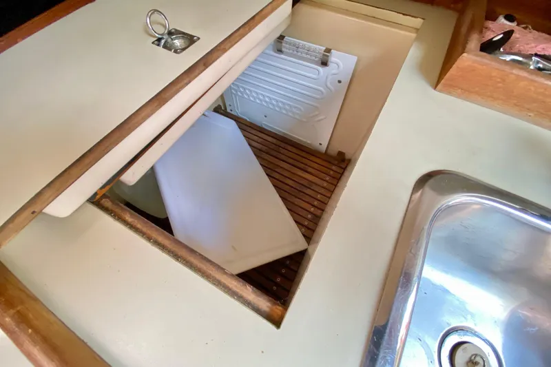 Slide: The Image of 1986 Bayfield 32 yacht galley with open storage compartment and stainless steel sink. - 23