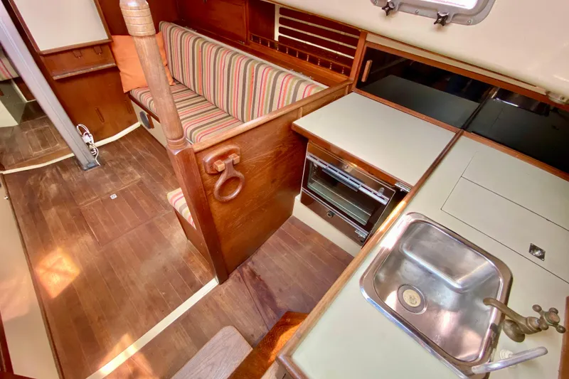Slide: The Image of Interior of 1986 Bayfield 32 sailboat with wood finish, striped seating, and compact kitchen area. - 25
