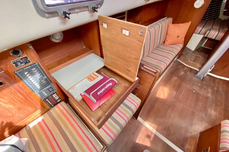Slide: The Image of 1986 Bayfield 32 sailboat interior with striped seating, wooden cabinetry, and navigation panel. - 29